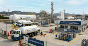 Vista do pátio de uma distribuidora de gás GLP com caminhões-tanque para abastecimento a granel, central de armazenamento e área de organização de cilindros de gás.